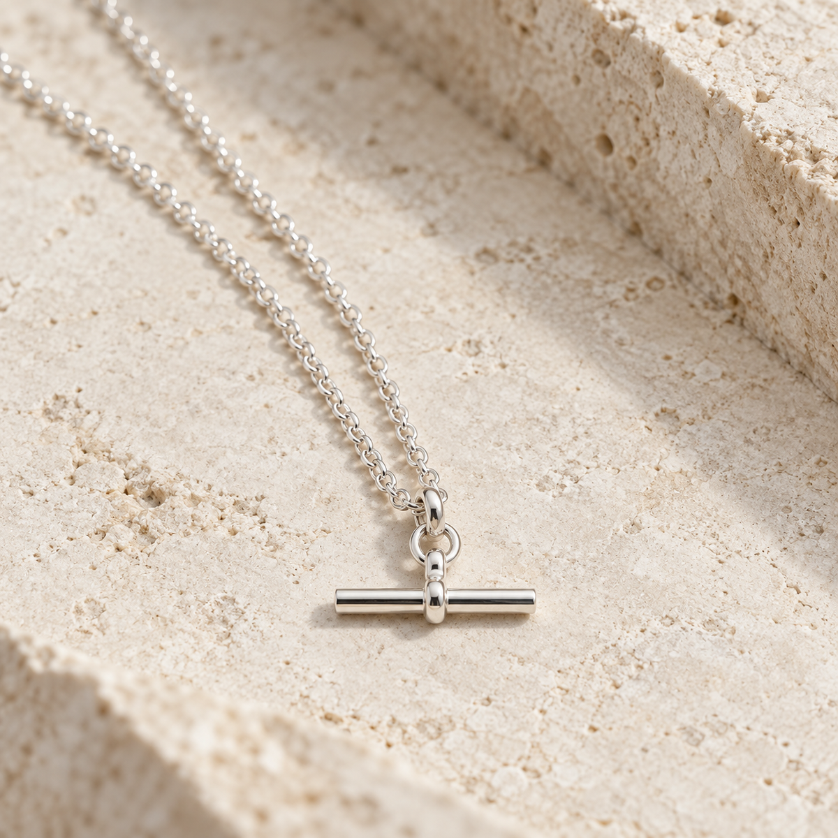 Silver T-Bar Chain on pale travertine in directional sunlight