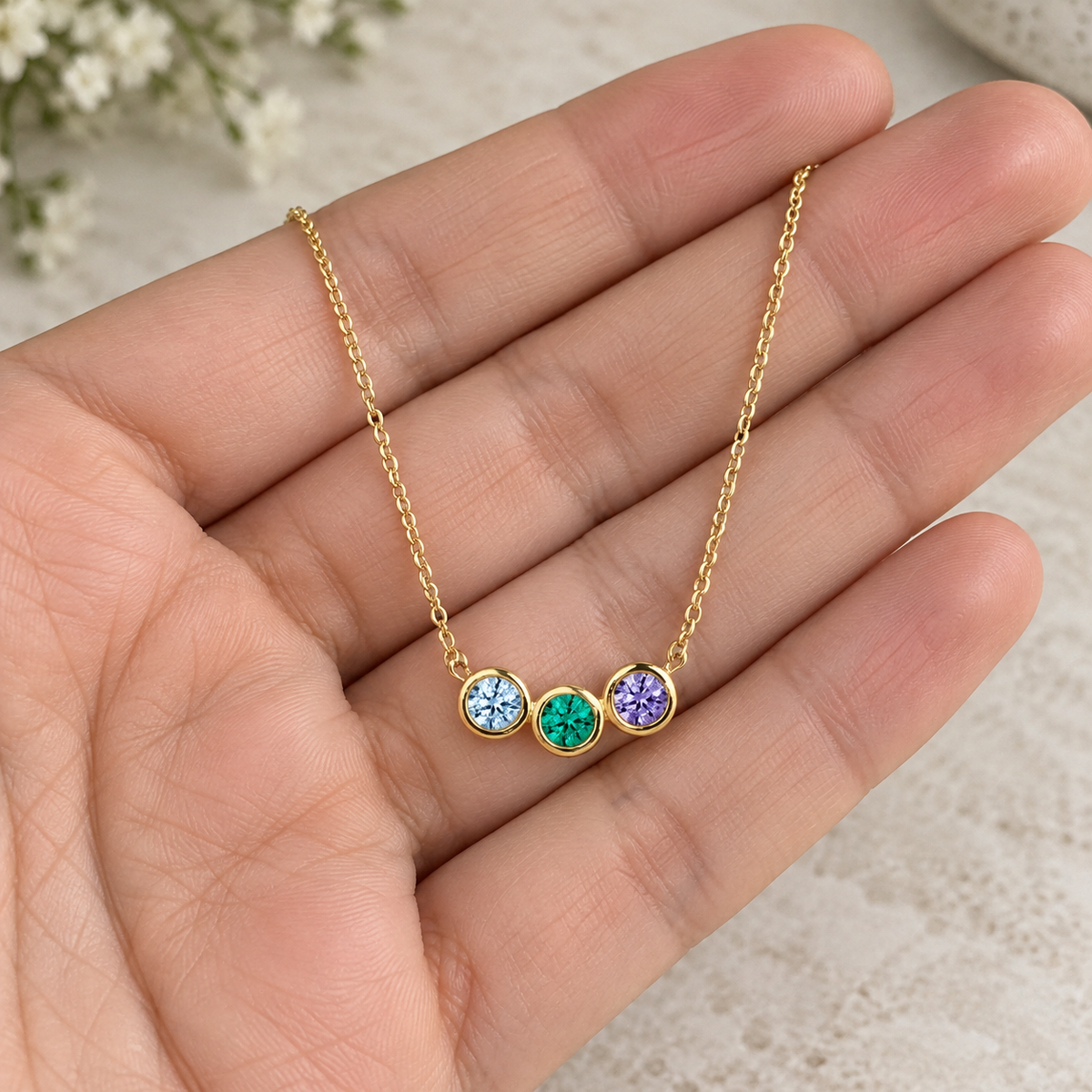 Three Stone Birthstone Necklace held in an open hand for scale