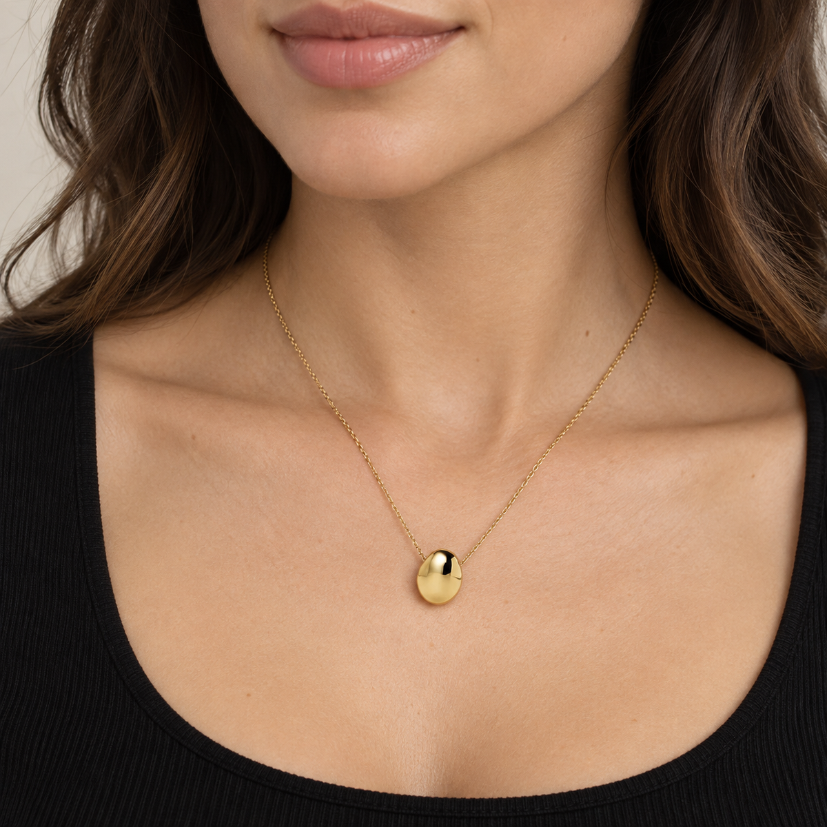 Model wearing the Gold Pebble Pendant Necklace with a black scoop-neck top