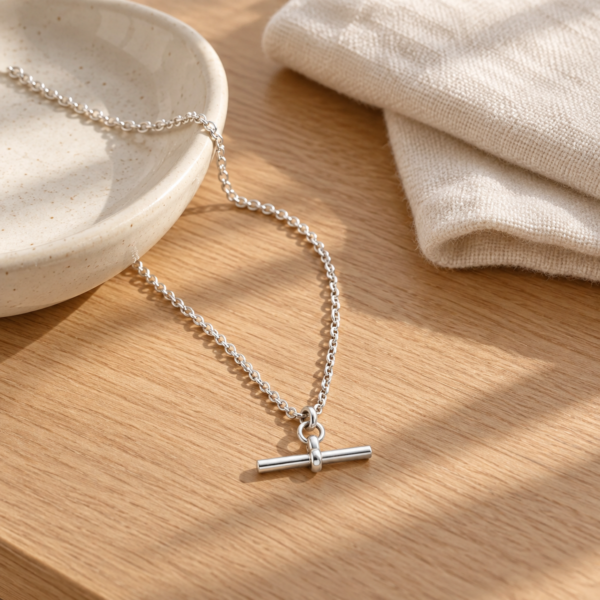 Silver T-Bar Chain on an oak surface beside a ceramic dish